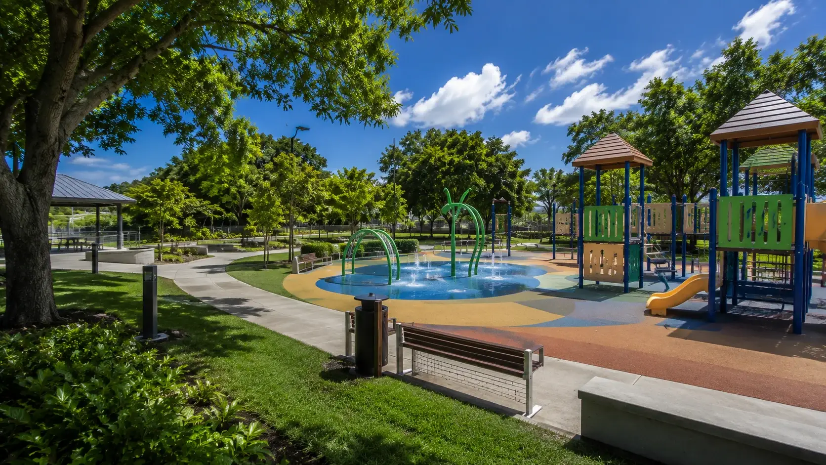 Modern family park in Guaynabo, Puerto Rico, featuring a colorful playground, splash pad, walking paths, picnic areas, and lush tropical landscaping.