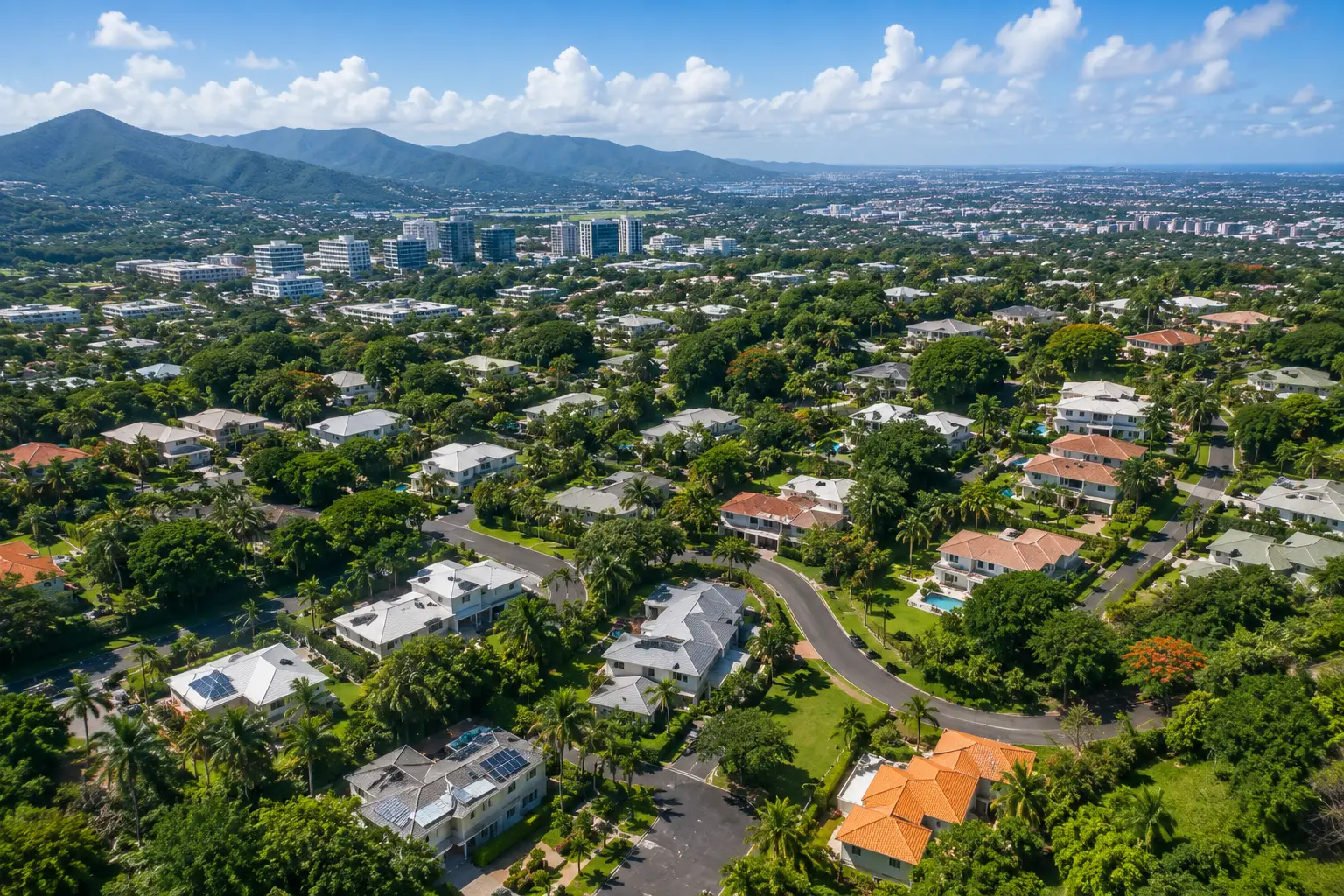 Aerial view of Garden Hills in Guaynabo, Puerto Rico, featuring luxury homes, tree-lined streets, tropical landscaping, and mountain views on a sunny day.