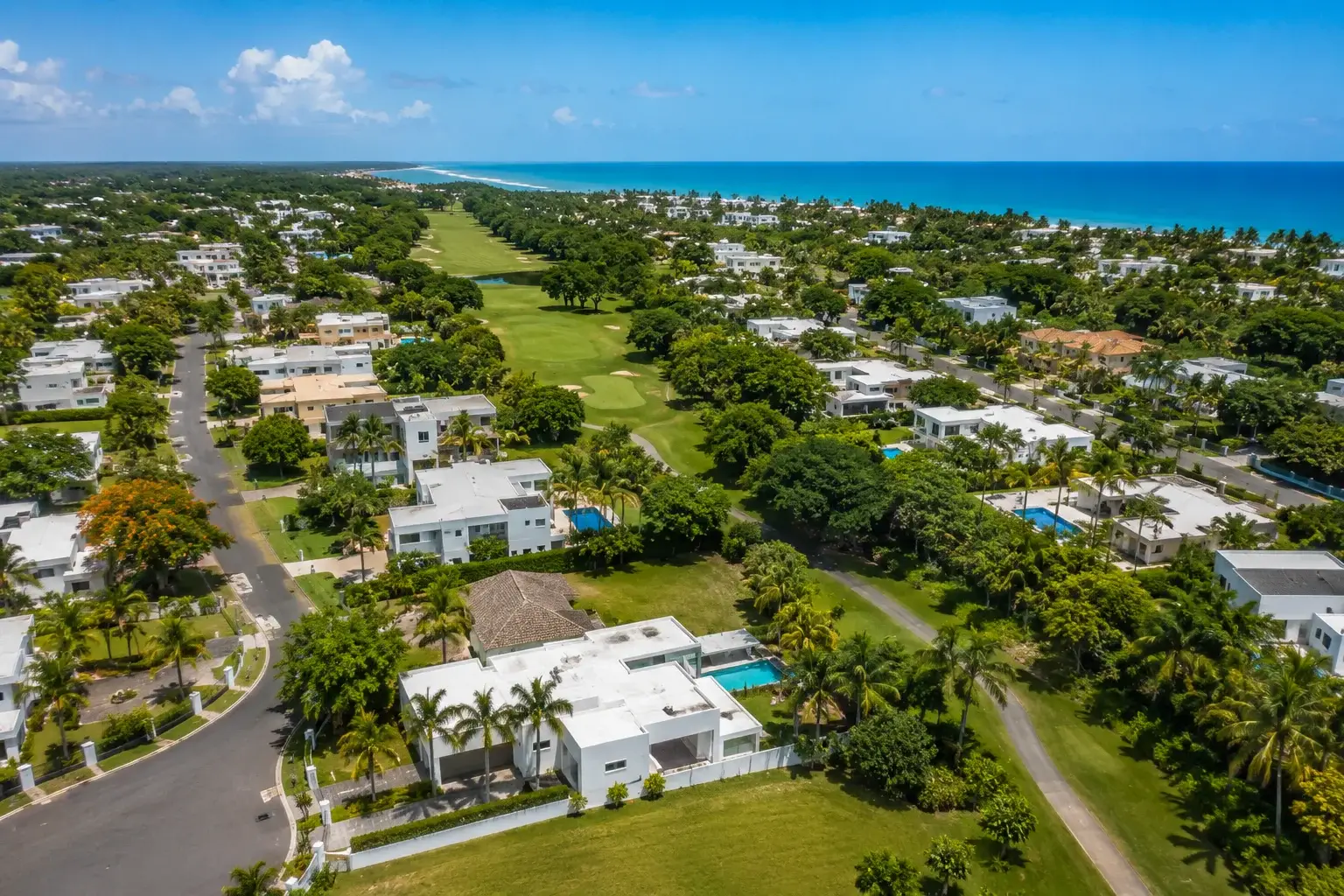 Aerial view of the Higuillar area in Dorado, Puerto Rico, featuring upscale residential neighborhoods, lush greenery, palm trees, and the Caribbean coastline.
