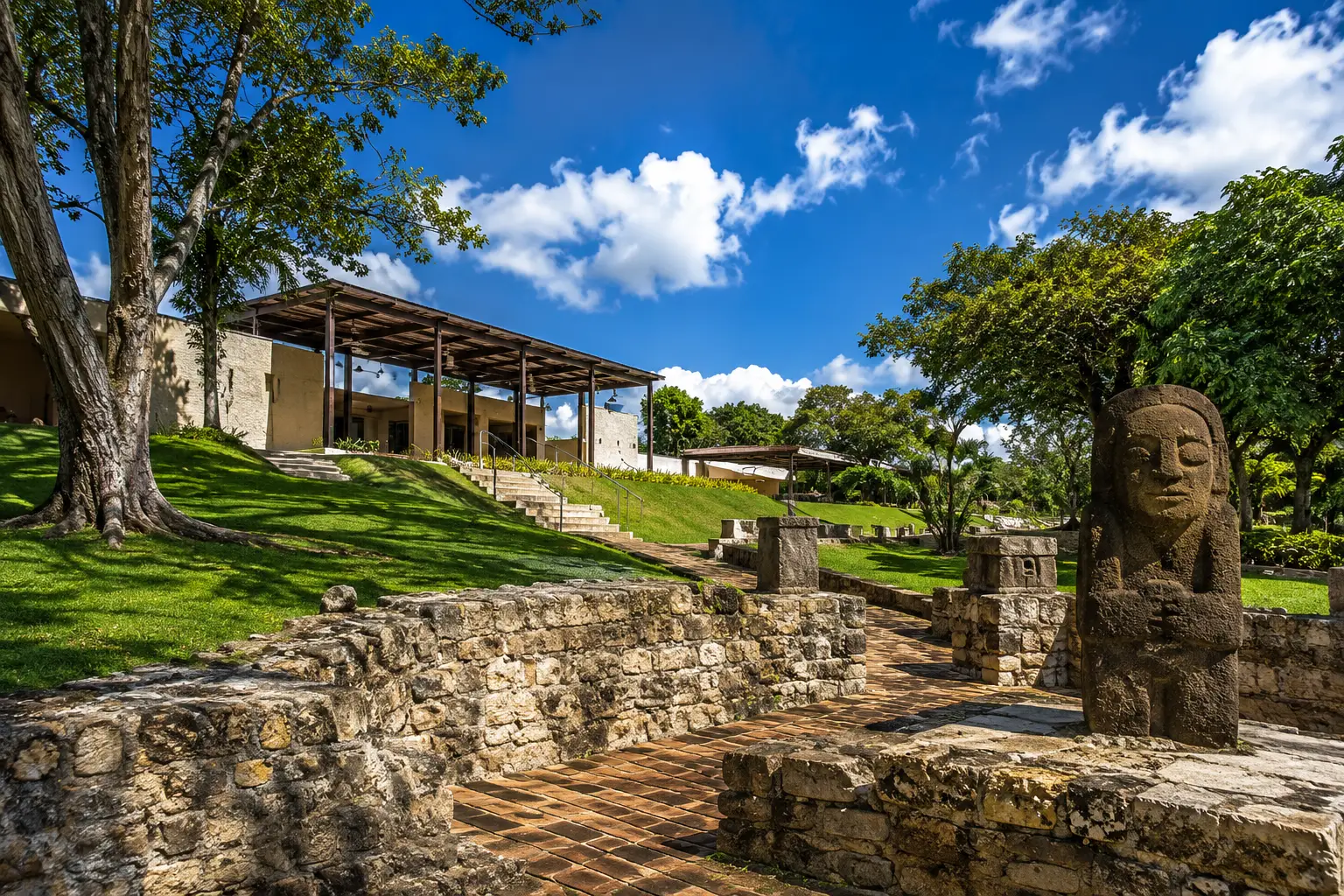 Scenic view of Museo y Parque Histórico de Caparra in Guaynabo, Puerto Rico, featuring preserved archaeological ruins, lush tropical gardens, walking paths, and the museum building.