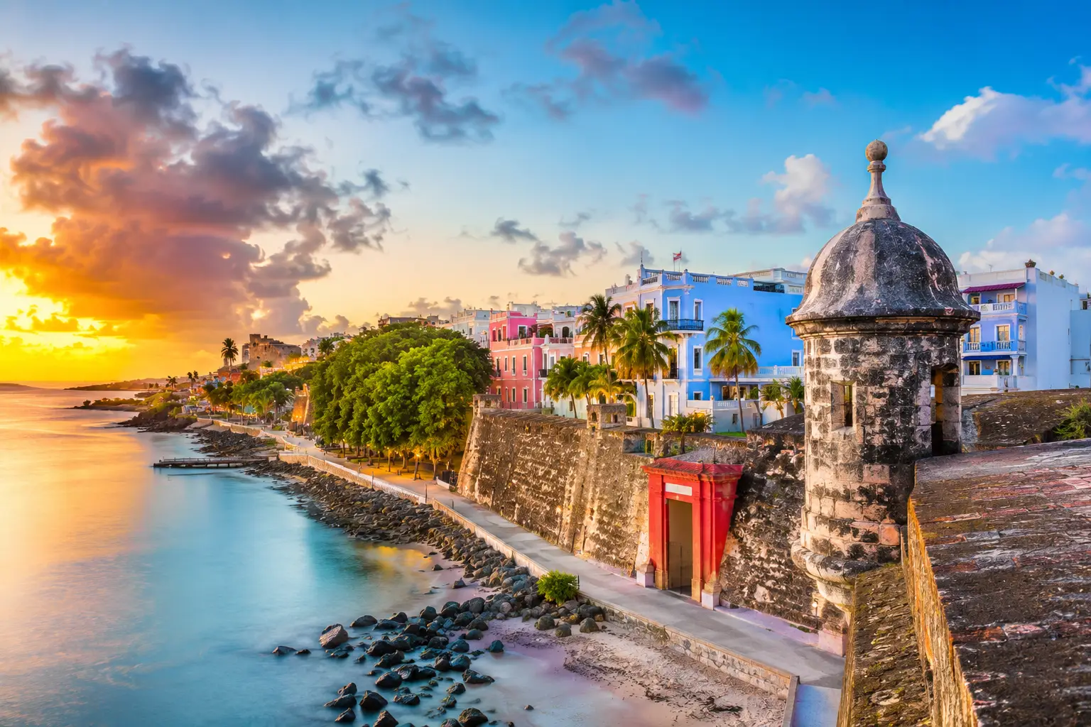 Colorful waterfront buildings and historic stone walls overlook the ocean in Old San Juan, Puerto Rico.