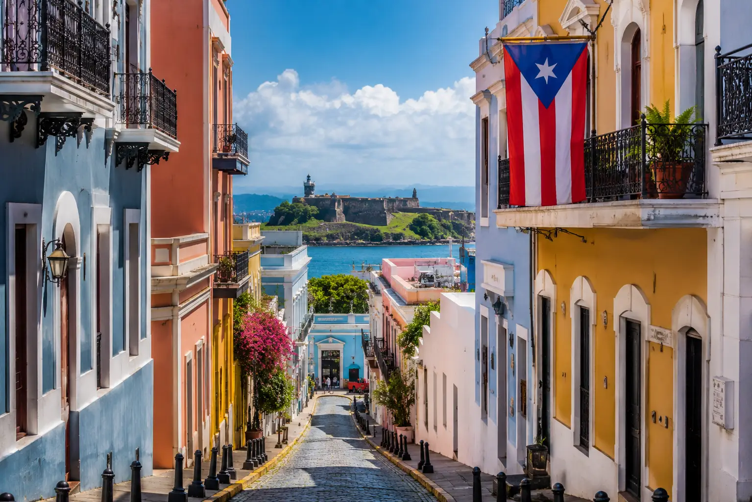 Colorful colonial buildings and a Puerto Rican flag line a cobblestone street overlooking the coast in Old San Juan.