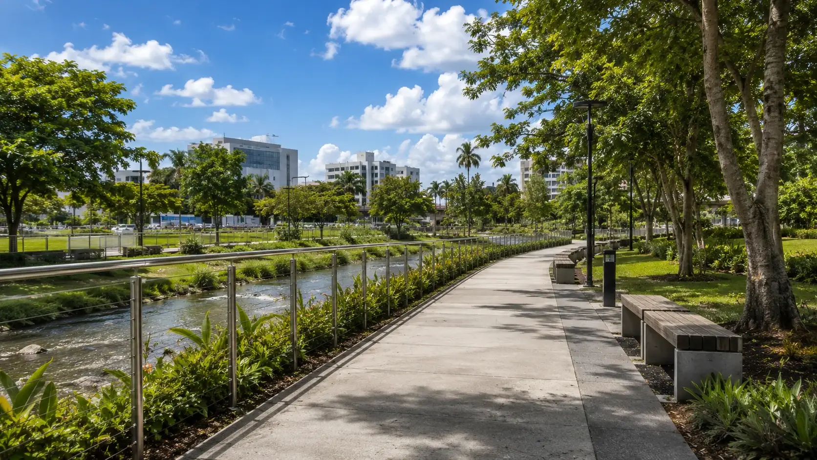 Tree-lined walking and cycling path at Paseo Lineal de Guaynabo, Puerto Rico, featuring landscaped gardens, a peaceful creek, modern lighting, and lush tropical vegetation.