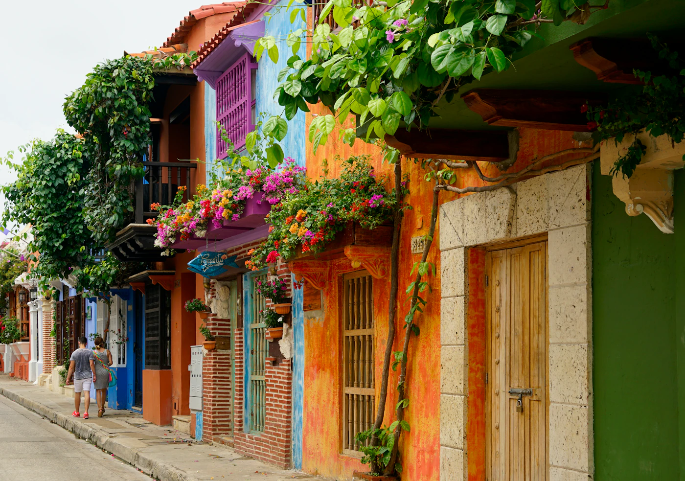 Colorful colonial houses have flower-covered balconies along a street in Cartagena, Colombia. Colorful colonial houses have flower-covered balconies along a street in Cartagena, Colombia.