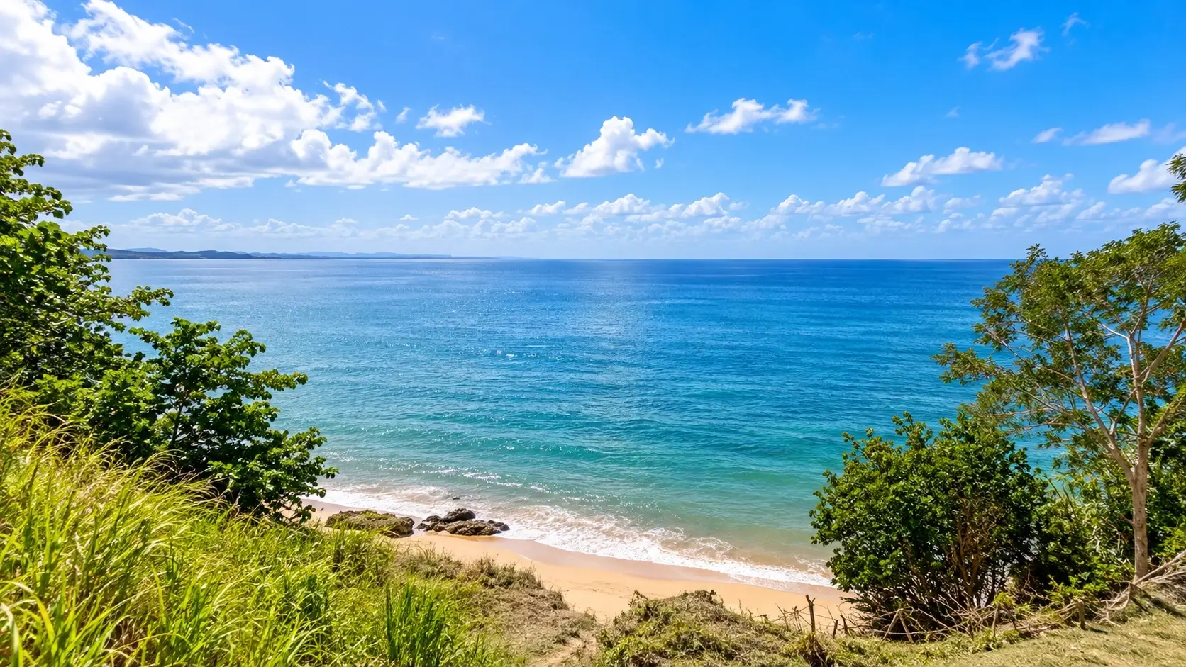 Scenic view of the Añasco Waterfront in Puerto Rico, with blue Caribbean waters, a sandy shoreline, tropical greenery, and a bright sky.