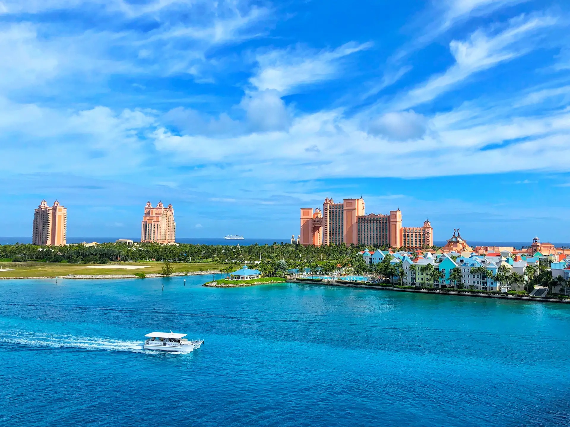 Atlantis towers and colorful waterfront buildings on Paradise Island, Bahamas, with a boat crossing turquoise water