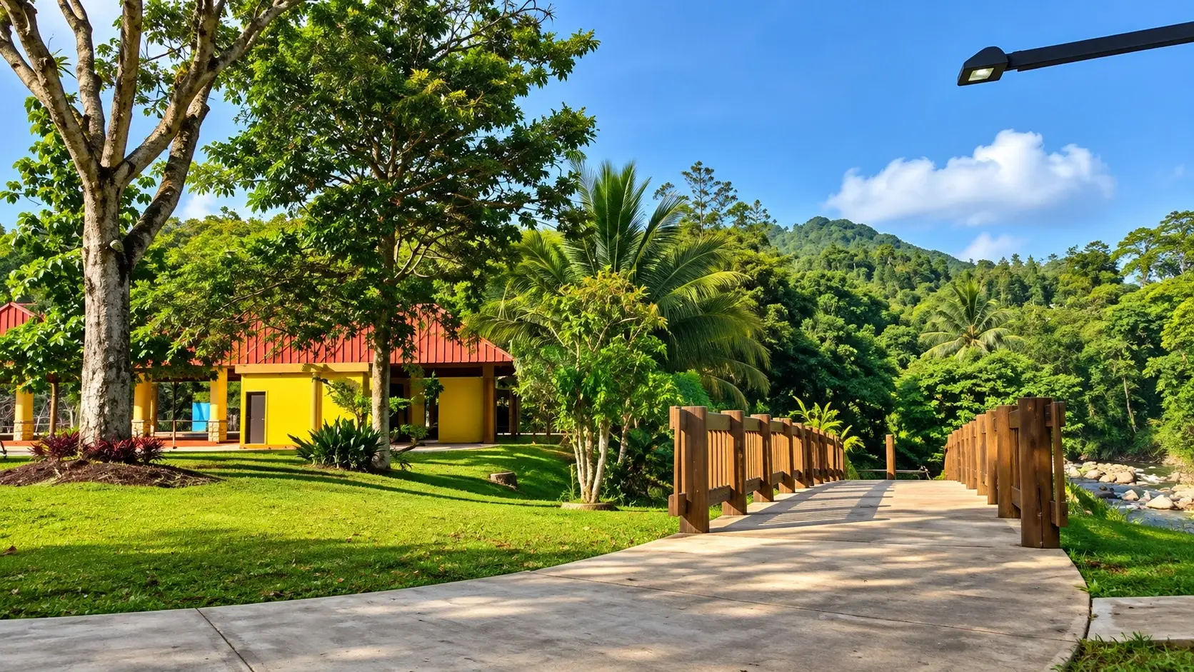 Scenic view representing Centro Recreativo La Charca in Aguas Buenas, Puerto Rico, with a pavilion, landscaped lawns, tropical vegetation, a walkway, and lush mountain scenery.