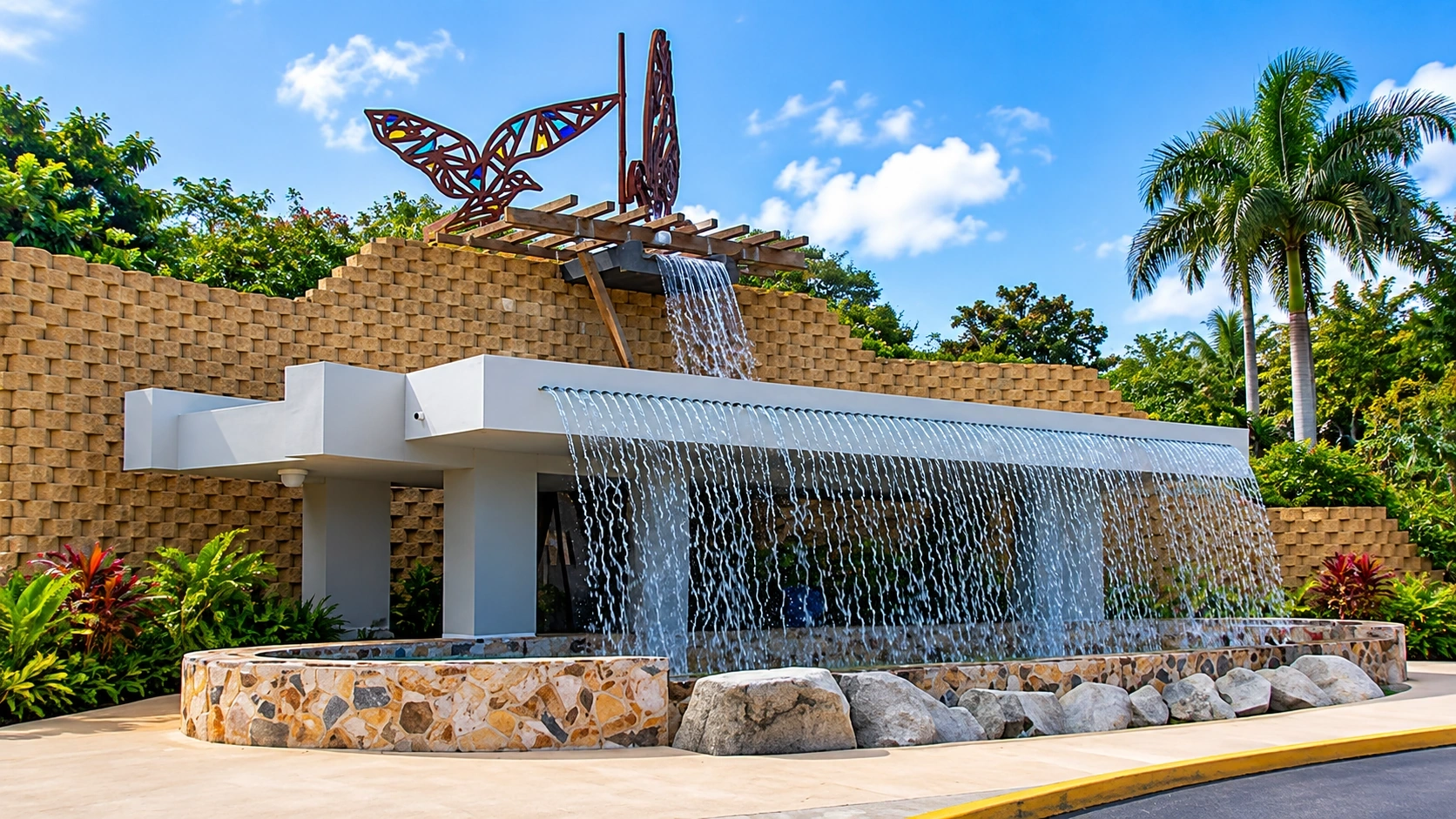 View representing the Historic Maximiliano Merced Fire Station in Aguas Buenas, Puerto Rico, with distinctive architecture, a cascading water feature, and tropical landscaping.