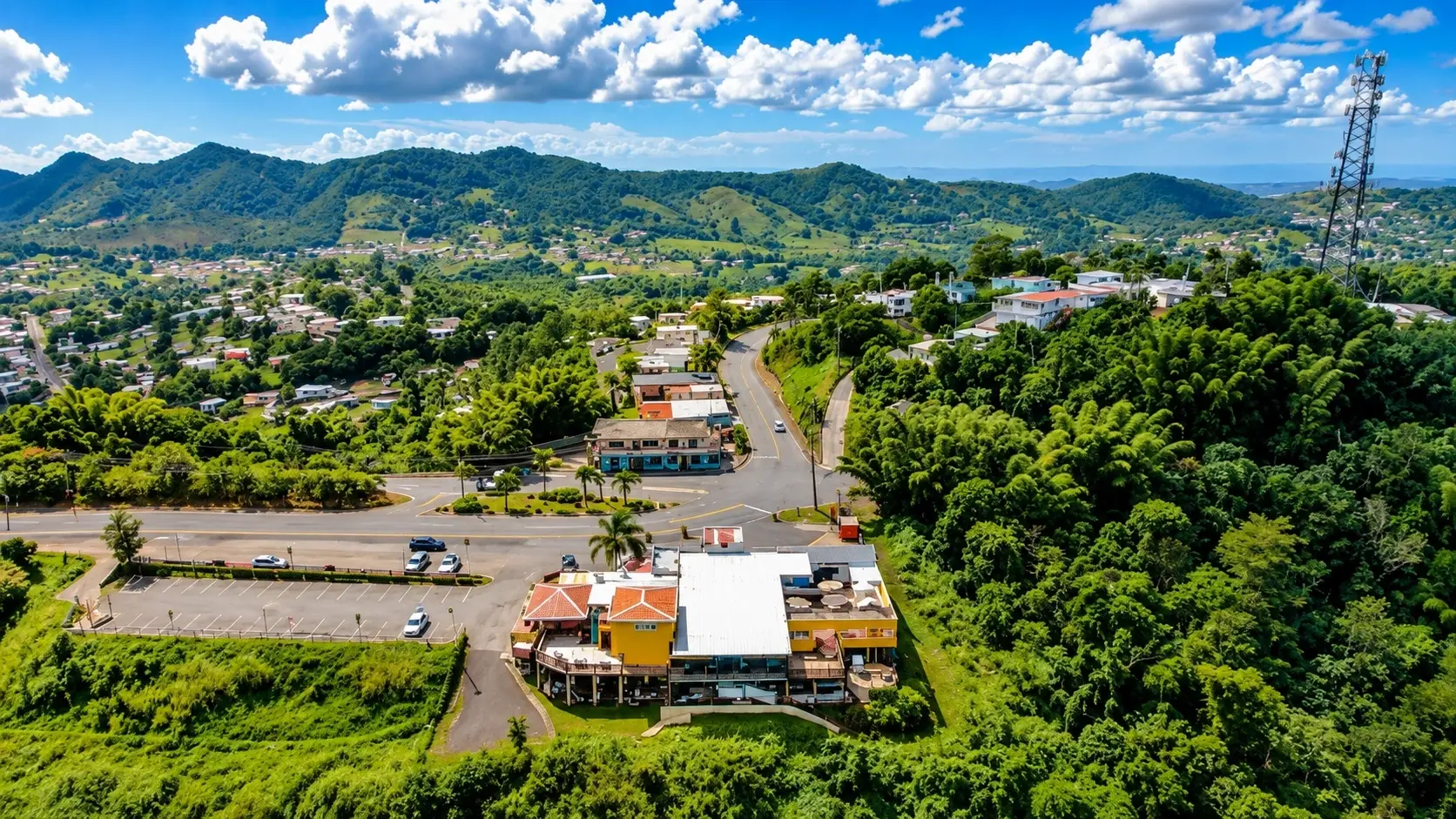 Aerial view of Pasto in Aibonito, Puerto Rico, featuring green mountains, winding roads, homes, and lush tropical vegetation.