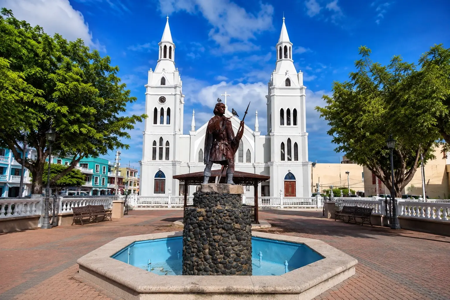 Plaza Cristóbal Colón in Aguadilla, Puerto Rico, with a historic monument and church architecture under a bright Caribbean sky.