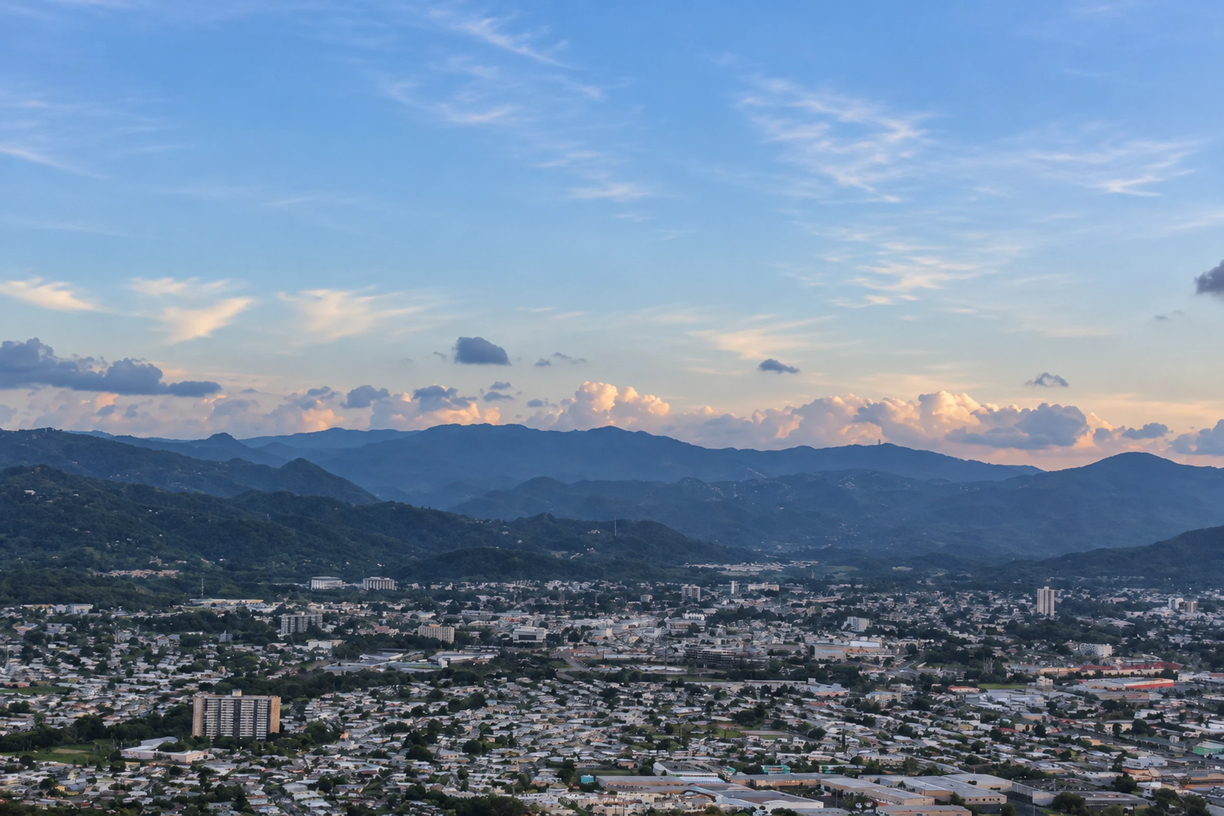 Caguas city and valley viewed from above, with mountains on the horizon.