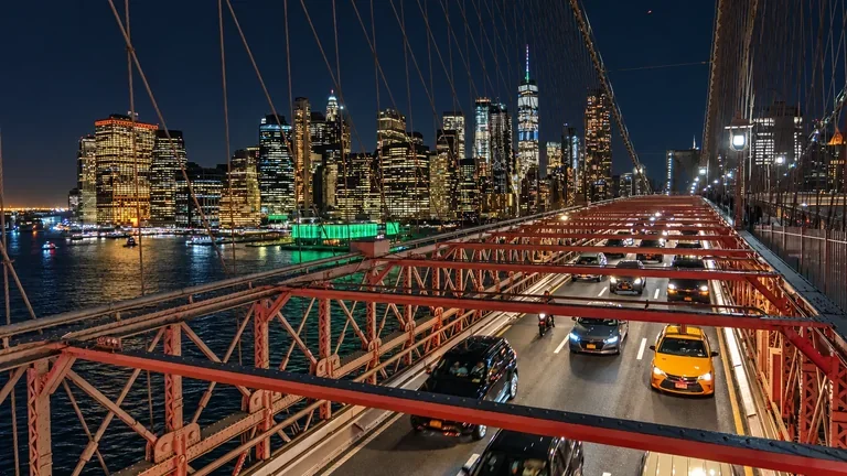 Brooklyn Bridge roadway with traffic and the illuminated Lower Manhattan skyline at night in New York City