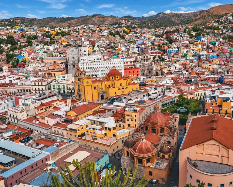 Colorful buildings spread across Guanajuato beneath surrounding hills.