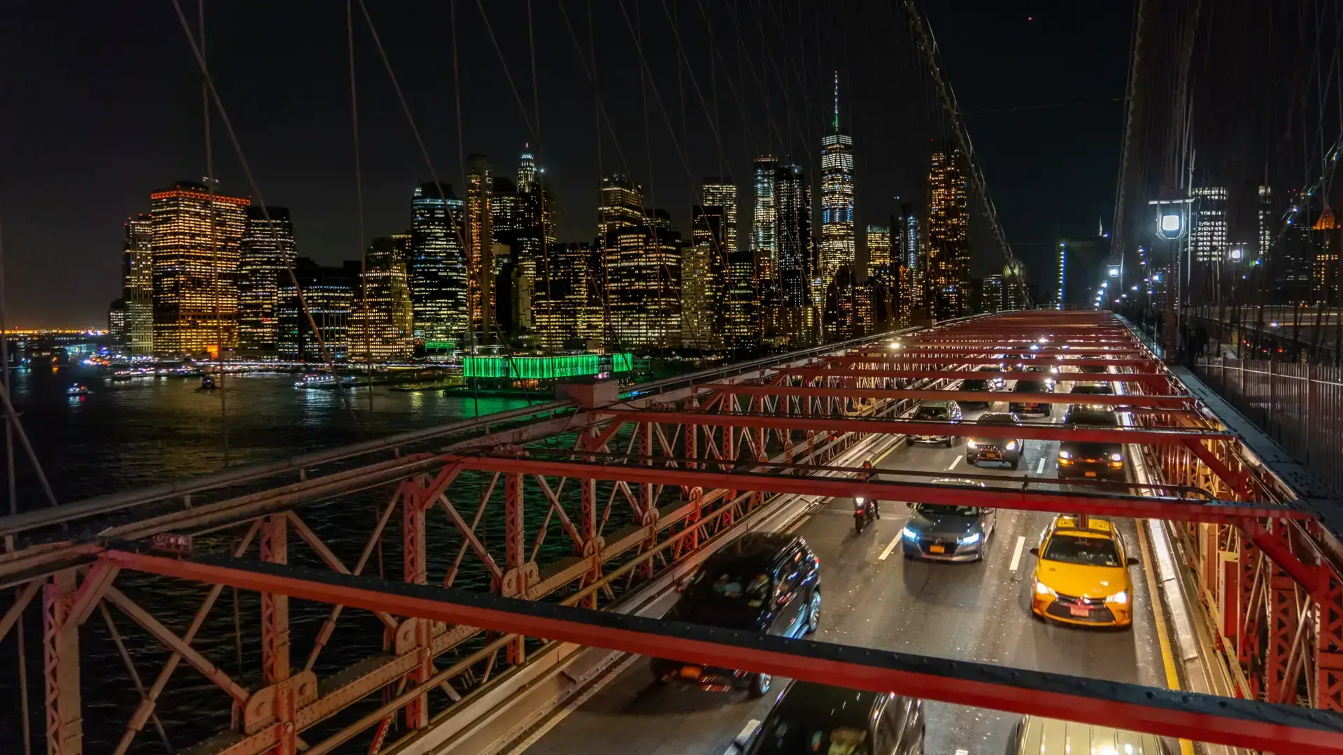 Brooklyn Bridge roadway with traffic and the illuminated Lower Manhattan skyline at night in New York City