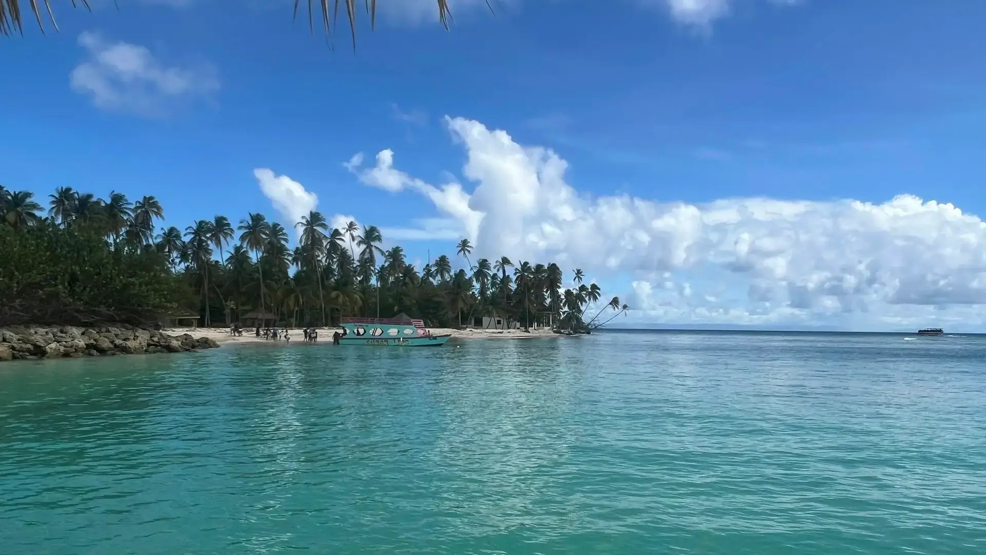 Turquoise water, a colorful boat and palm-lined Crown Point Beach in Tobago