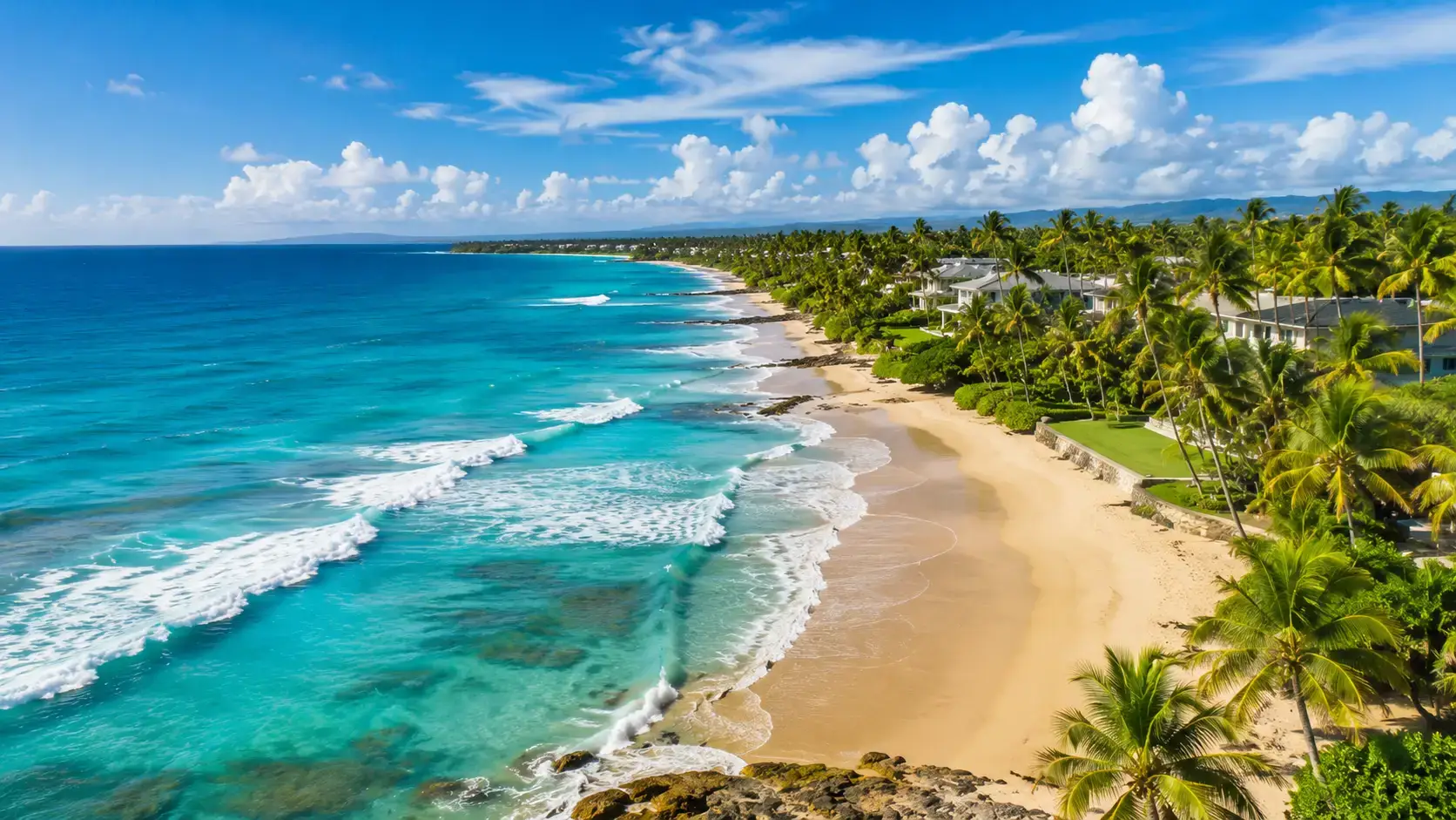 Turquoise waves meet a sandy beach lined with palms and coastal homes in Dorado, Puerto Rico.