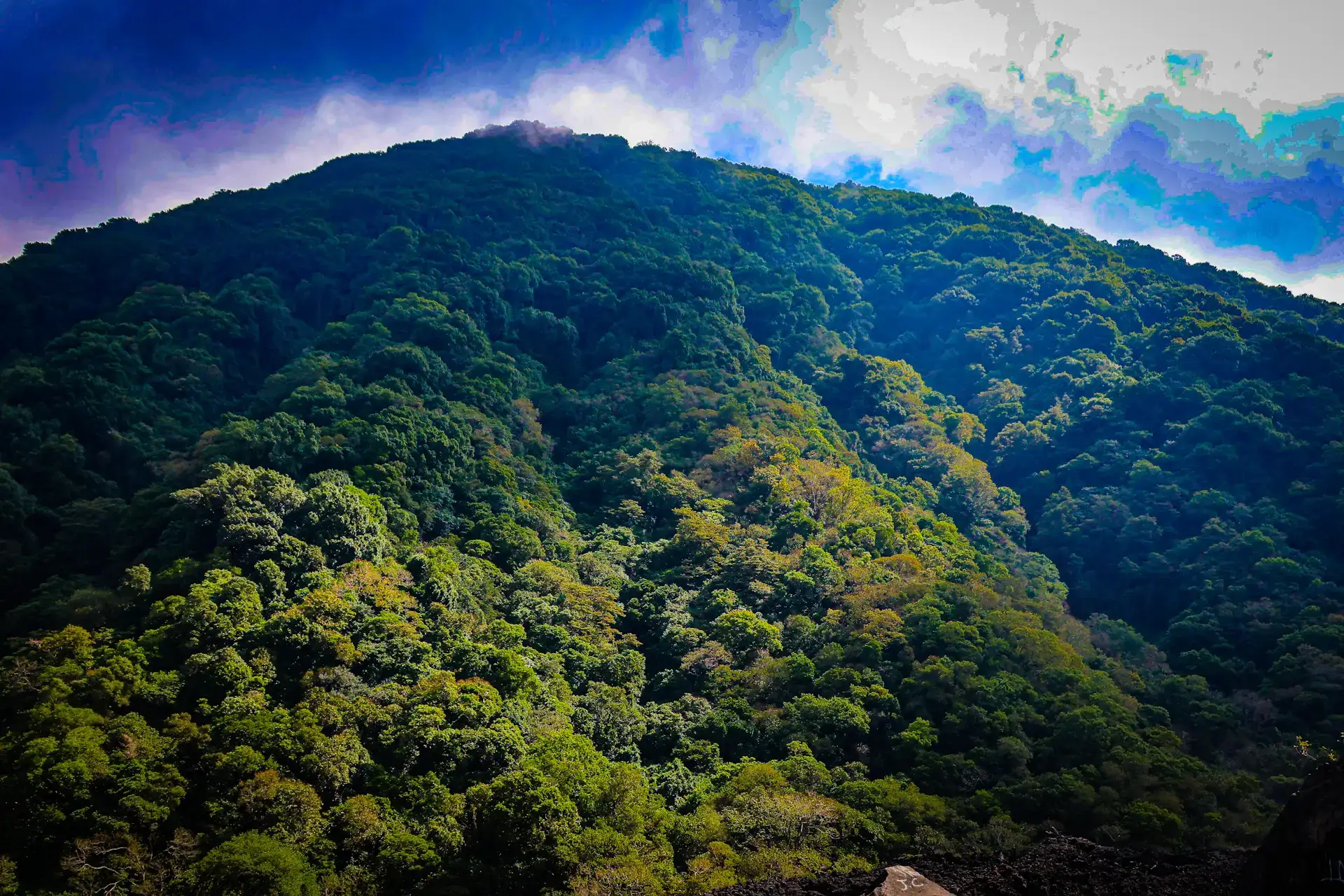 Lush green mountain beneath blue sky and clouds at Cerro Verde National Park, El Salvador