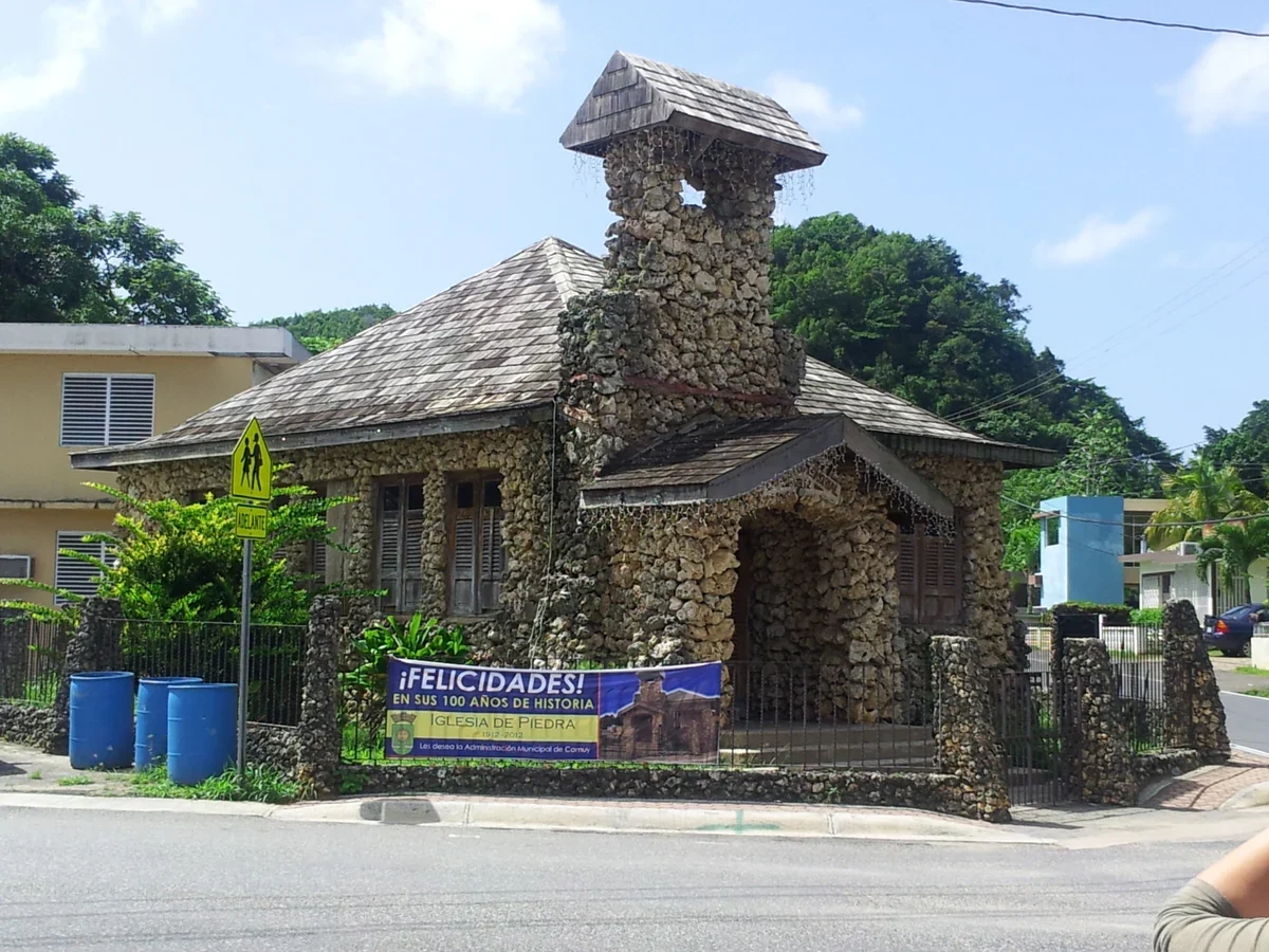 Stone chapel and square bell tower beside the street at Ernesto Memorial Chapel, also known as Iglesia de Piedra, in Abra Honda, Camuy, Puerto Rico.
