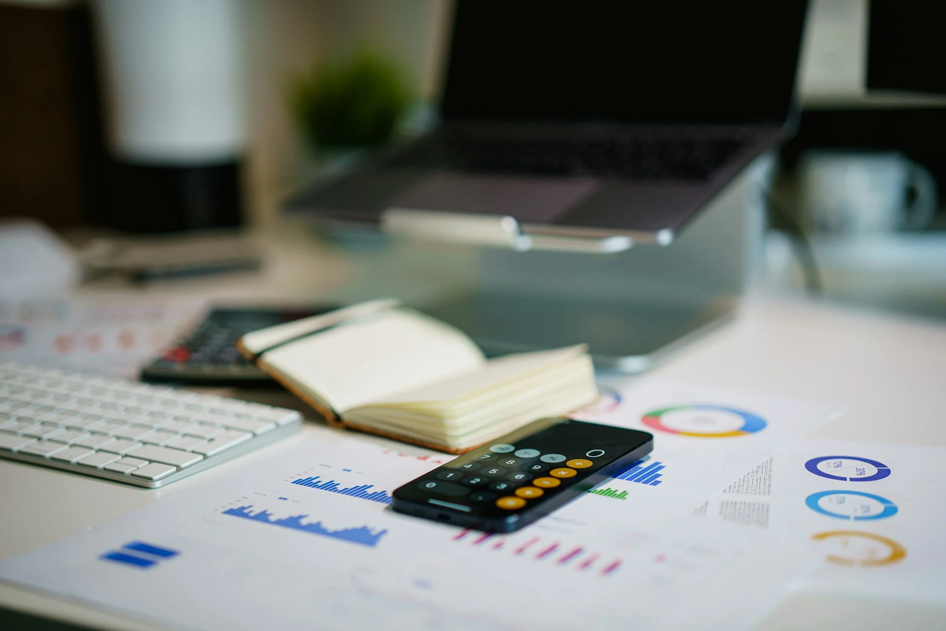 Calculator and financial reports on a desk for reviewing costs and expenses.