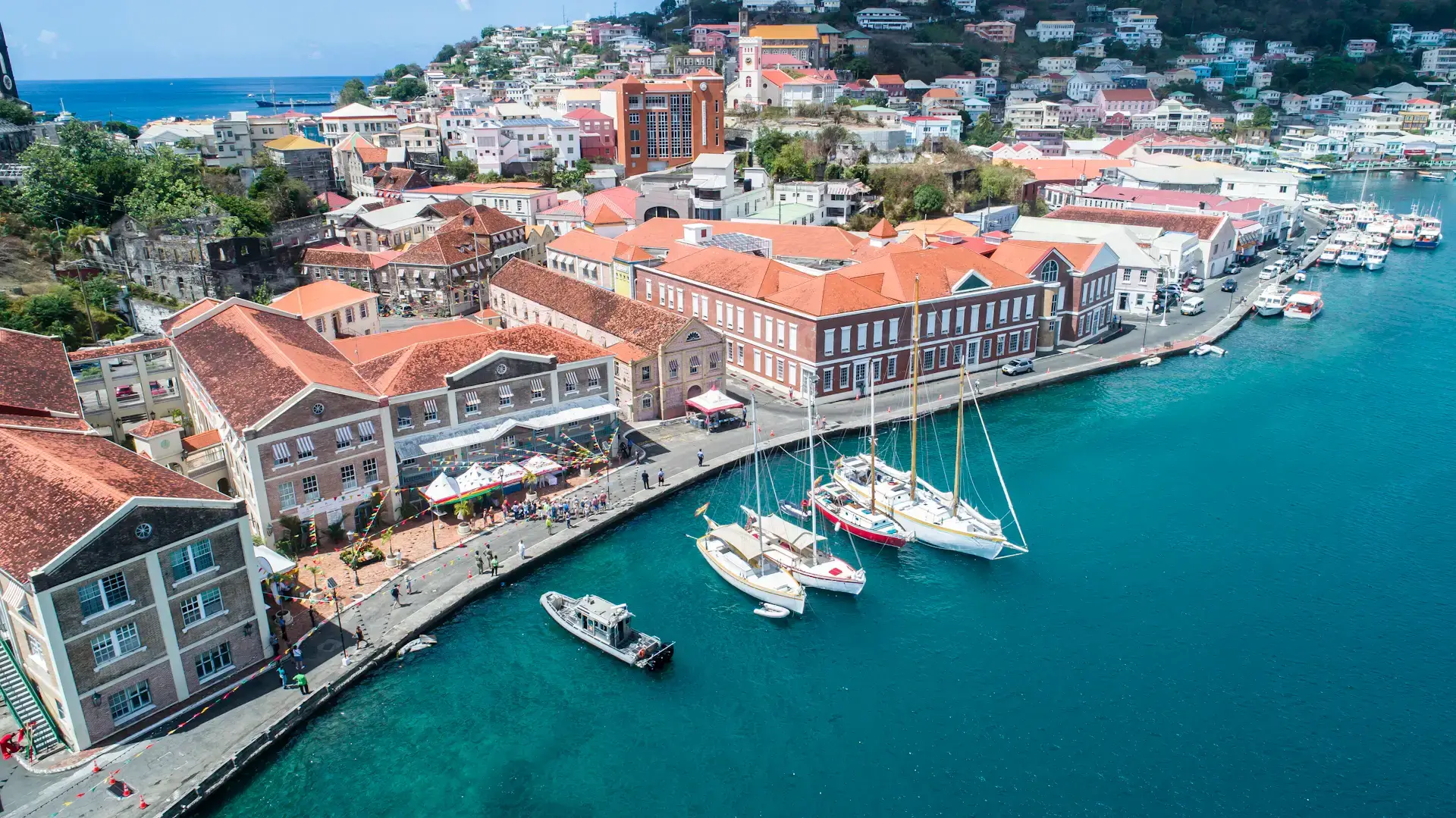 Aerial view of colorful waterfront buildings and sailboats in turquoise water at Saint George’s Harbour, Grenada
