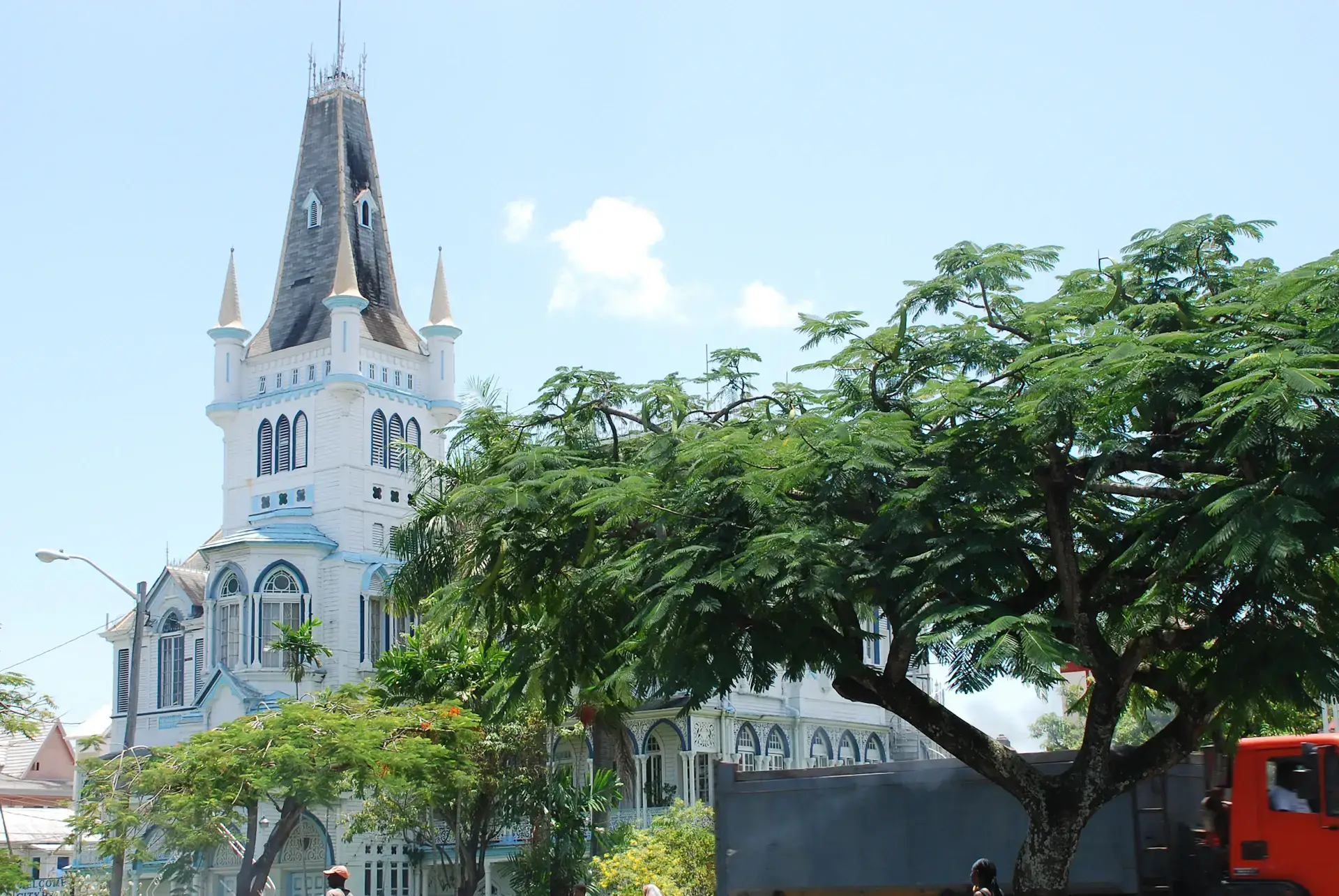 White wooden cathedral framed by green trees under a bright blue sky in Georgetown, Guyana