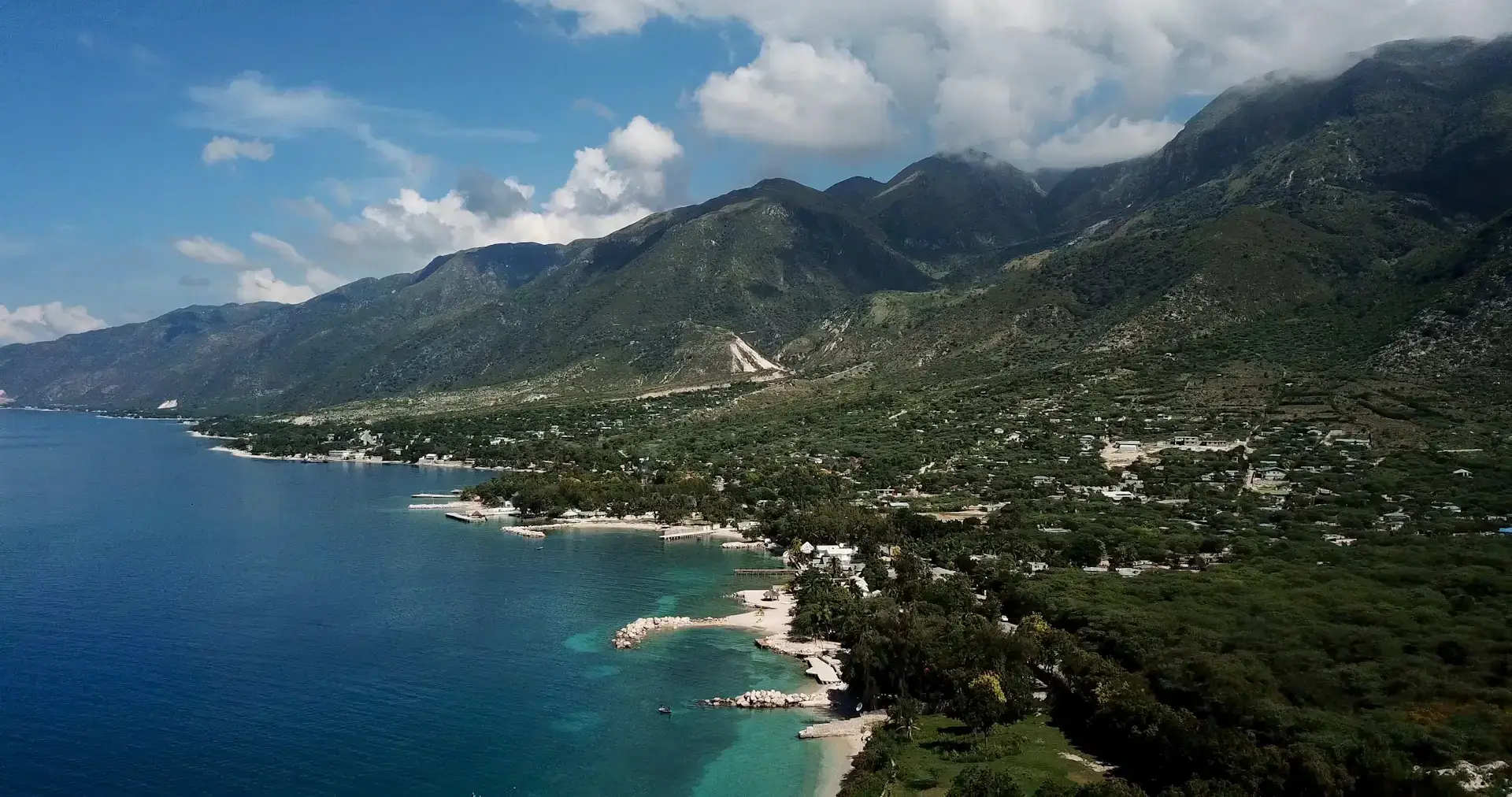 Aerial view of Haiti’s coastal settlements, turquoise bays and green mountain slopes