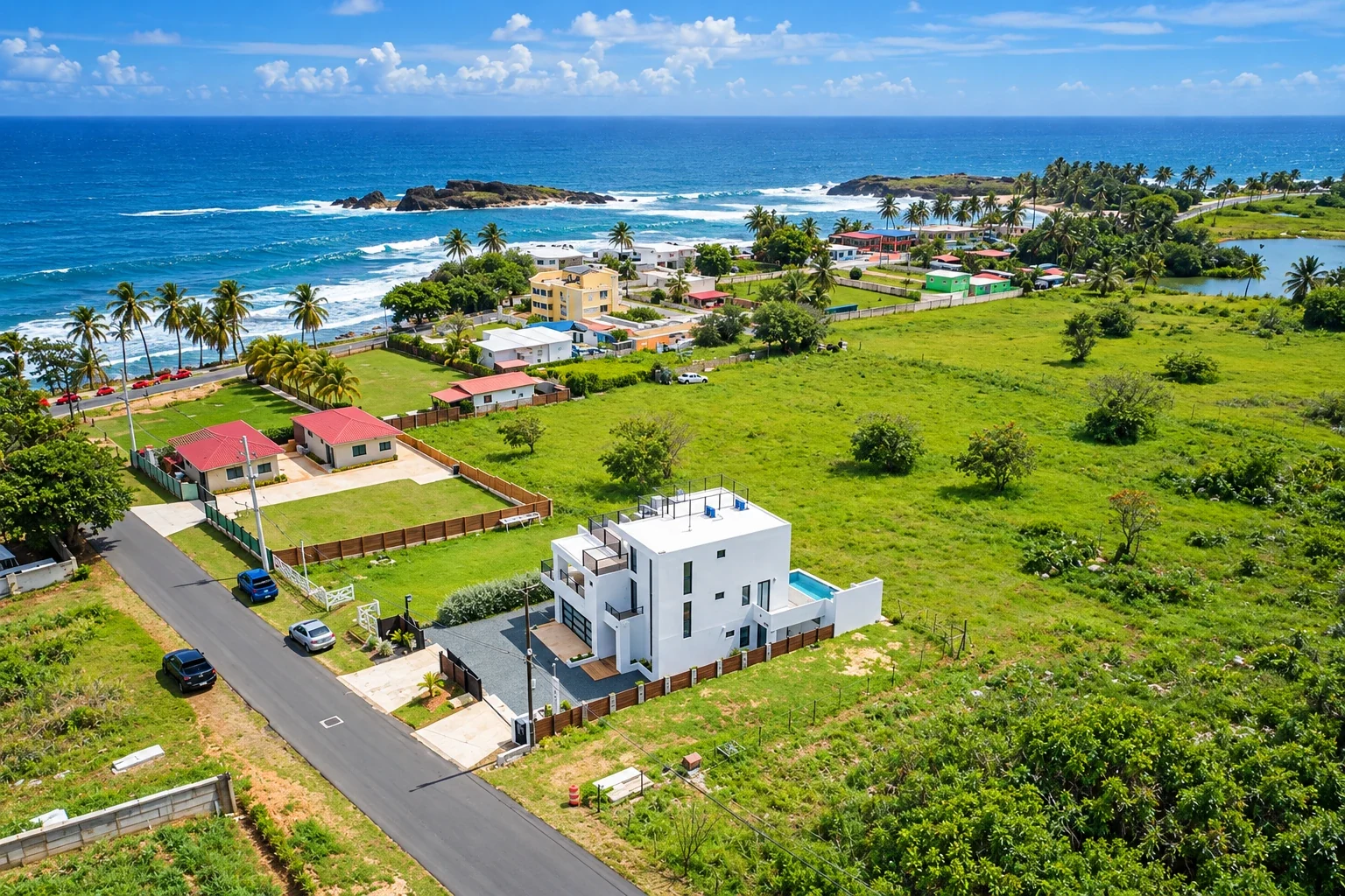 AI-generated aerial illustration showing a white house, scattered coastal homes, paved roads, green fields, palms and ocean waves, based on a Membrillo reference.