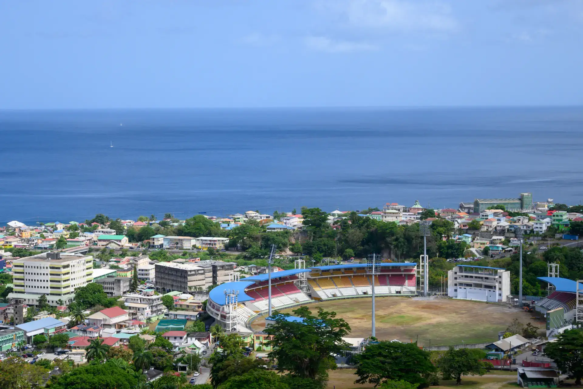 Roseau city buildings and a large stadium beside the blue Caribbean Sea in Dominica