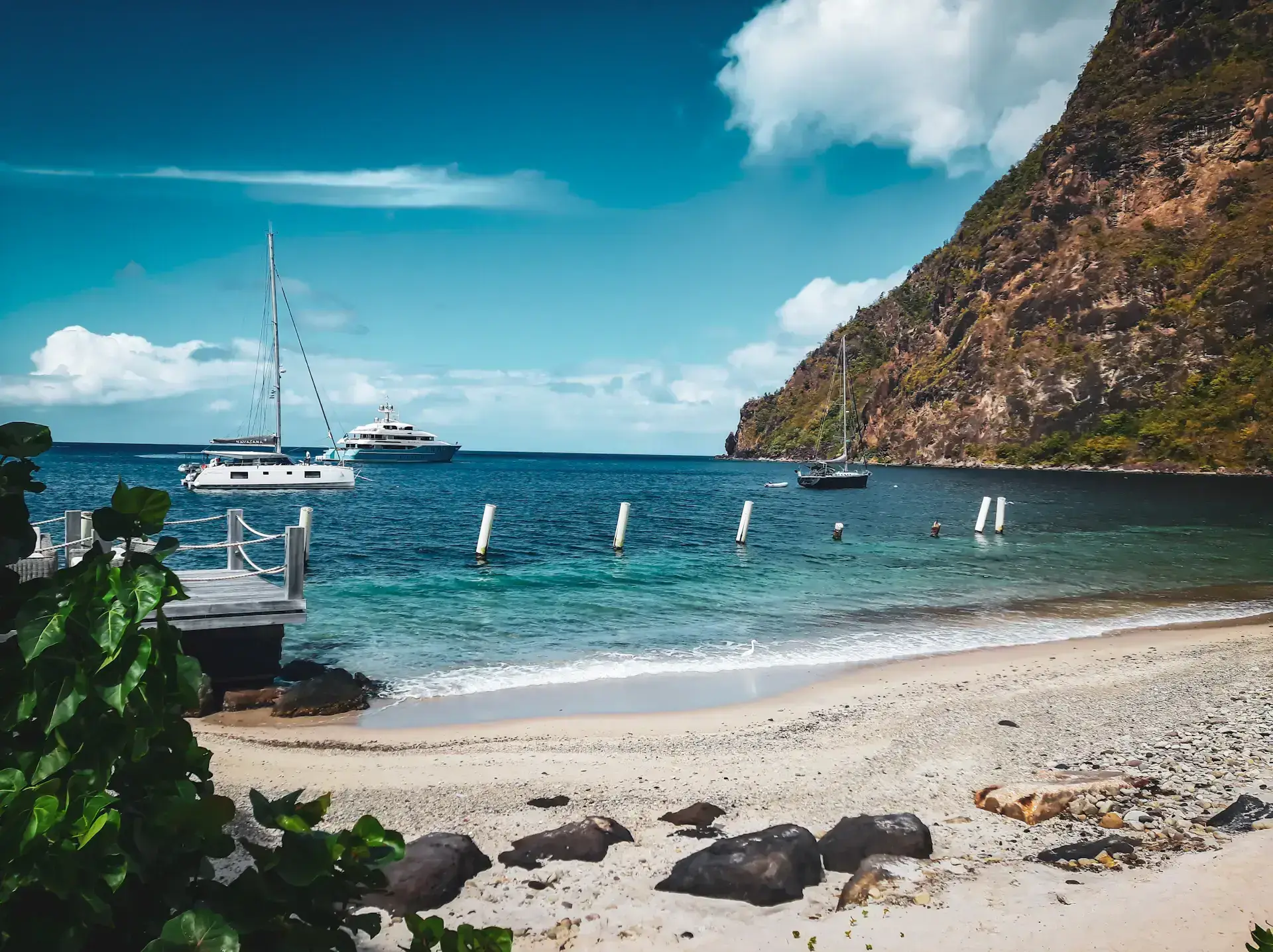 Sailing boats, turquoise Caribbean water and a coastal hillside in Saint Lucia